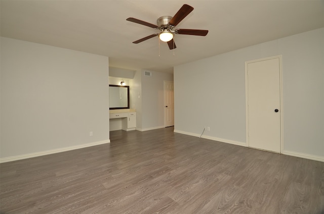 unfurnished room featuring ceiling fan, built in desk, and dark hardwood / wood-style floors