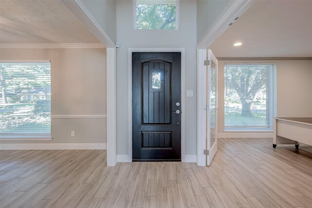 entrance foyer with crown molding and light hardwood / wood-style floors