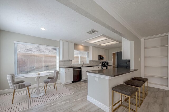 kitchen featuring sink, kitchen peninsula, a breakfast bar, white cabinets, and appliances with stainless steel finishes