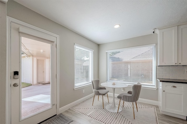 dining area with light wood-type flooring and a textured ceiling