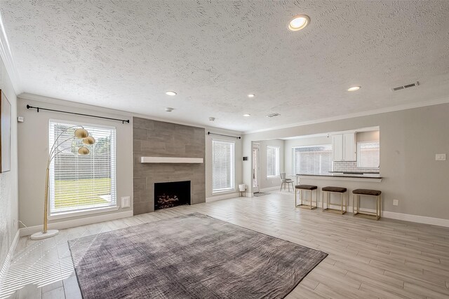 living room featuring a tile fireplace, a textured ceiling, and ornamental molding