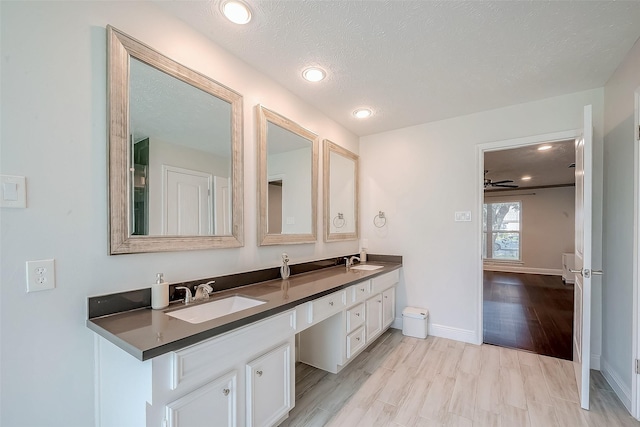 bathroom featuring hardwood / wood-style floors, vanity, ceiling fan, and a textured ceiling