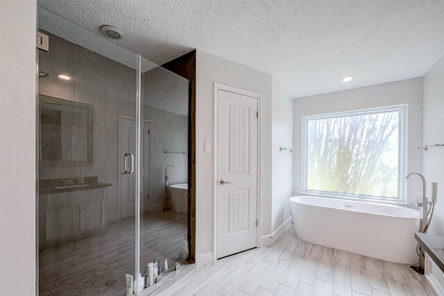 bathroom with shower with separate bathtub, a textured ceiling, and sink