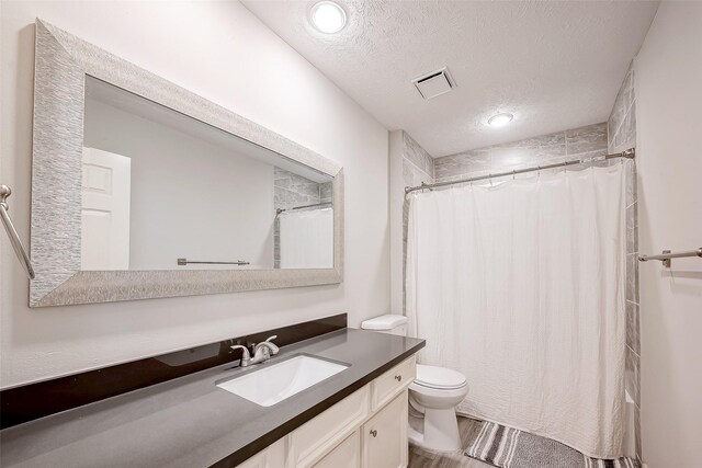 bathroom with curtained shower, vanity, a textured ceiling, and toilet