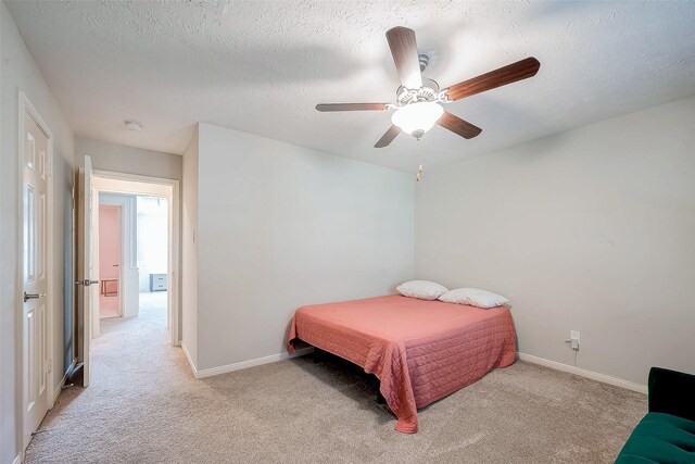 bedroom featuring ceiling fan, light colored carpet, and a textured ceiling