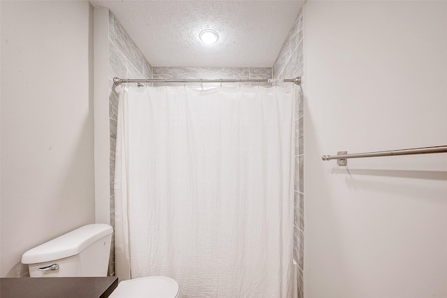 bathroom featuring a shower with shower curtain, a textured ceiling, and toilet