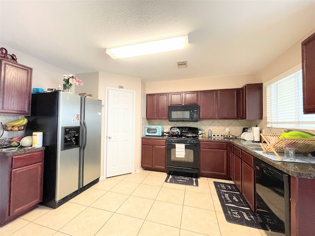 kitchen with backsplash, light tile patterned floors, black appliances, and a textured ceiling