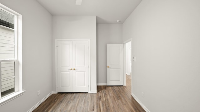 unfurnished bedroom with ceiling fan, a closet, and wood-type flooring