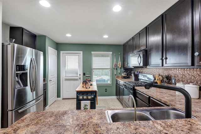 kitchen featuring backsplash, light stone countertops, sink, and black appliances