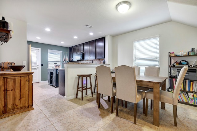 dining space with light tile patterned flooring, a healthy amount of sunlight, and lofted ceiling