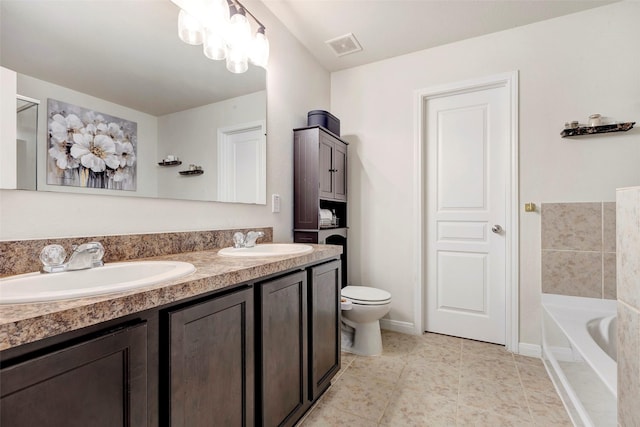 bathroom featuring toilet, vanity, tile patterned floors, and a tub