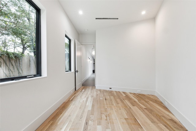 empty room with light hardwood / wood-style floors and plenty of natural light