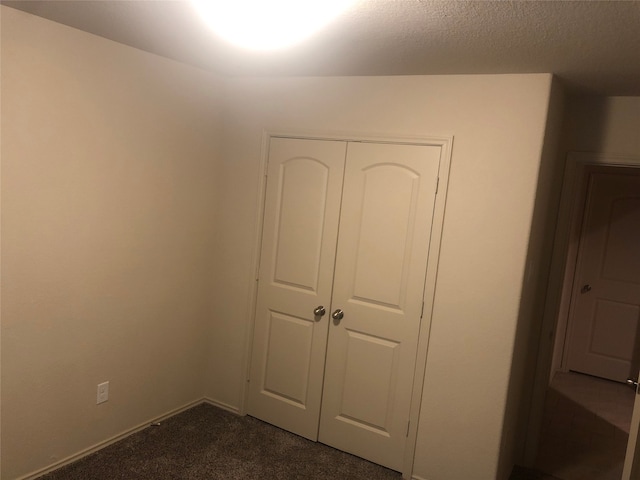 unfurnished bedroom with a closet and dark colored carpet