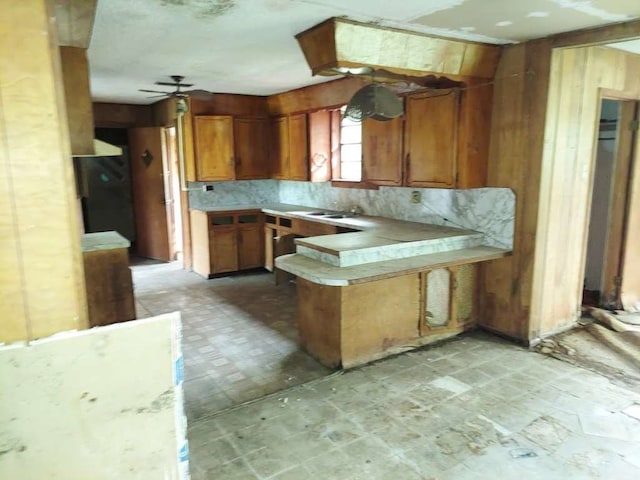 kitchen with kitchen peninsula, backsplash, ceiling fan, and sink