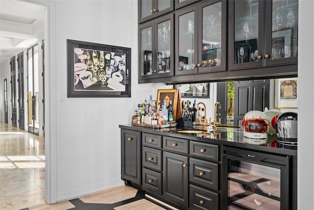 bar featuring wine cooler, sink, dark stone countertops, and light wood-type flooring