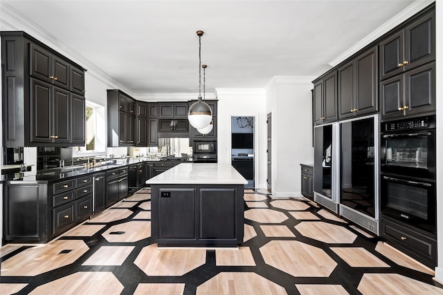 kitchen with crown molding, a kitchen island, black appliances, and decorative light fixtures