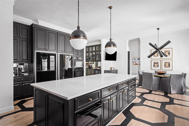 kitchen with ornamental molding, black double oven, light hardwood / wood-style flooring, a kitchen island, and hanging light fixtures