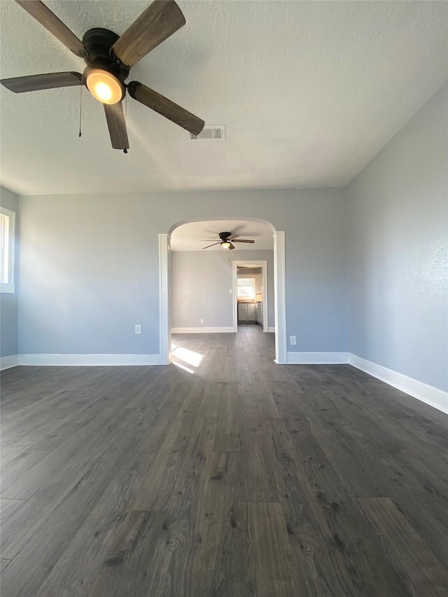 unfurnished living room with ceiling fan, dark wood-type flooring, and a textured ceiling