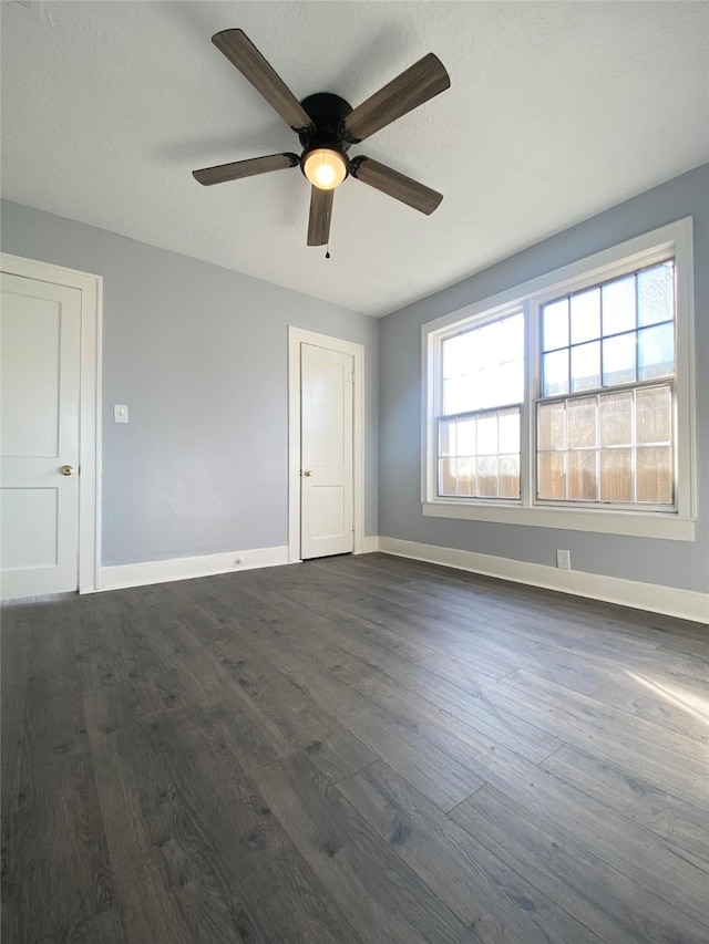 spare room with plenty of natural light, ceiling fan, and dark wood-type flooring