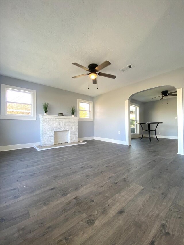 unfurnished living room featuring a fireplace, ceiling fan, and dark wood-type flooring