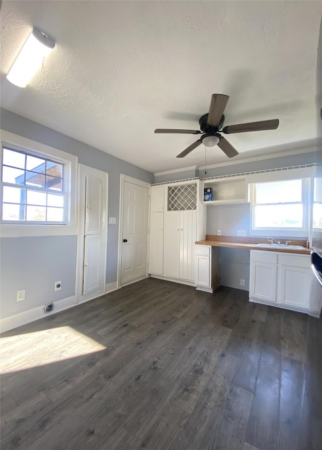 unfurnished office featuring ceiling fan, sink, dark hardwood / wood-style flooring, a textured ceiling, and built in desk