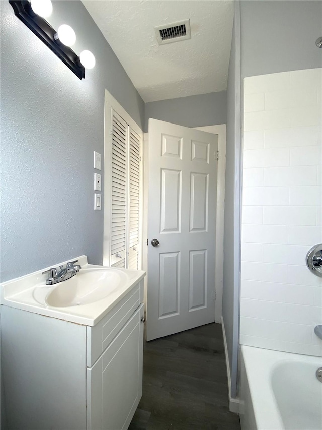 bathroom featuring hardwood / wood-style flooring, vanity, washtub / shower combination, and a textured ceiling