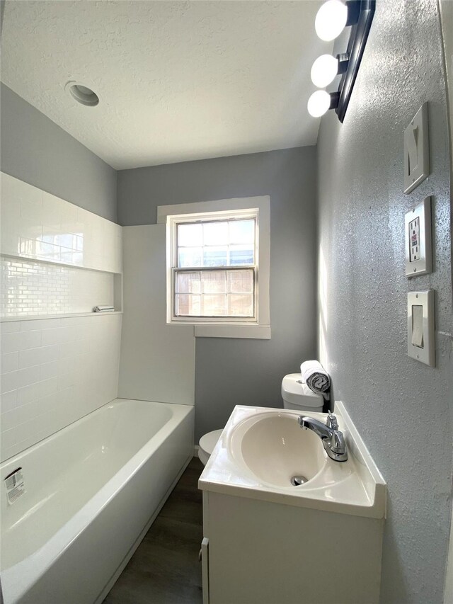 bathroom with hardwood / wood-style floors, vanity, toilet, and a textured ceiling