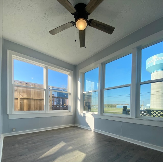 unfurnished sunroom featuring ceiling fan and a healthy amount of sunlight