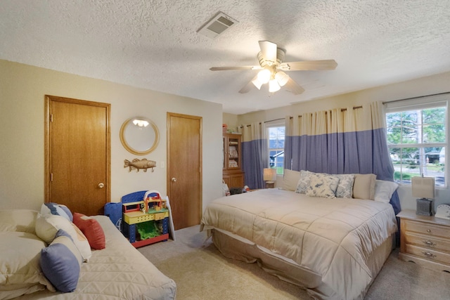 bedroom with light carpet, a textured ceiling, and ceiling fan