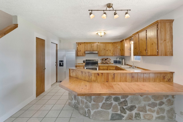 kitchen featuring kitchen peninsula, a textured ceiling, stainless steel appliances, and sink