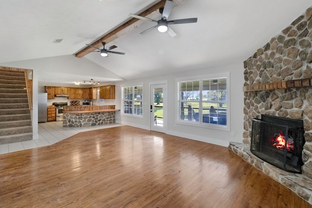 unfurnished living room with vaulted ceiling with beams, ceiling fan, light hardwood / wood-style flooring, and a fireplace