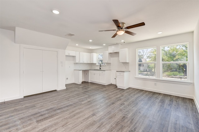 unfurnished living room with light hardwood / wood-style floors, ceiling fan, and sink