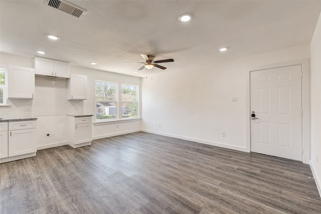 unfurnished living room with ceiling fan and dark wood-type flooring