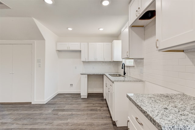 kitchen with light stone countertops, white cabinetry, sink, and light hardwood / wood-style flooring