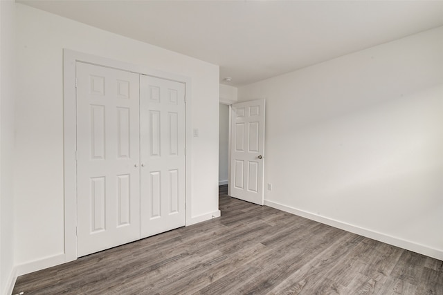 unfurnished bedroom featuring dark hardwood / wood-style flooring and a closet