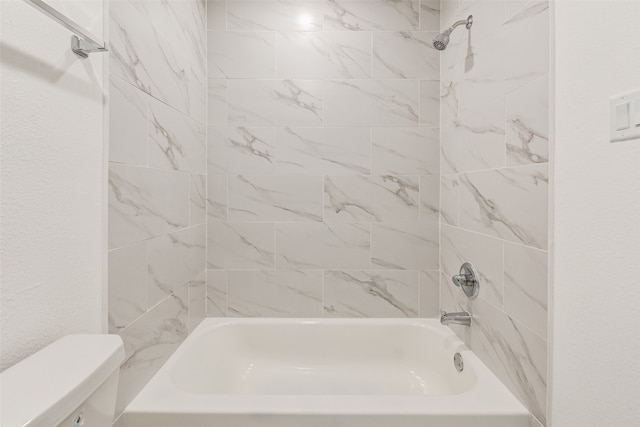 bathroom featuring tiled shower / bath combo and toilet