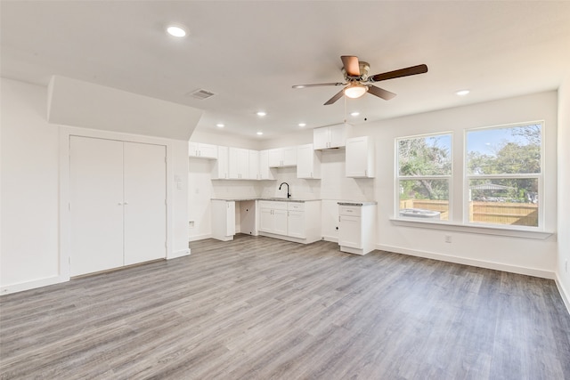 unfurnished living room with light wood-type flooring, ceiling fan, and sink