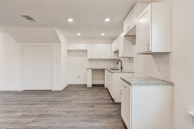 kitchen with white cabinetry, sink, and light hardwood / wood-style flooring