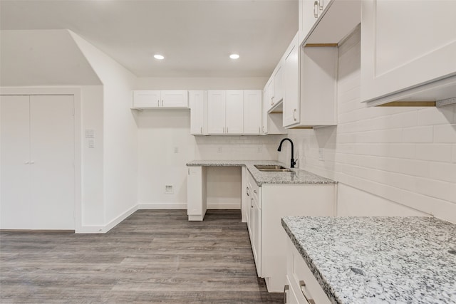 kitchen with light stone countertops, sink, light hardwood / wood-style floors, decorative backsplash, and white cabinets