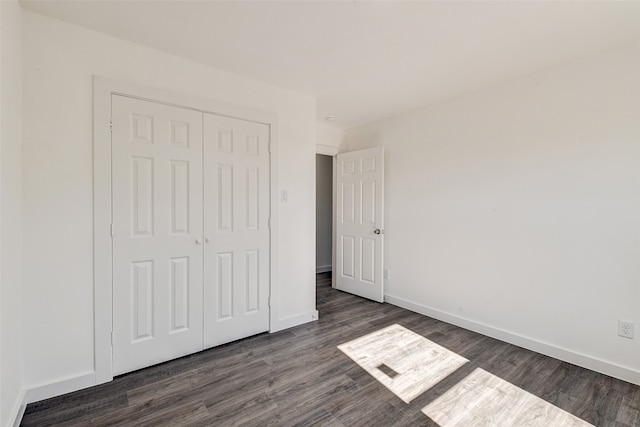 unfurnished bedroom featuring a closet and dark wood-type flooring