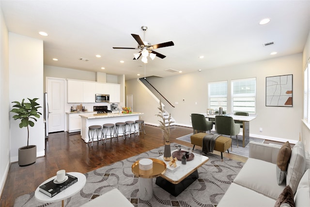 living room with ceiling fan and dark wood-type flooring