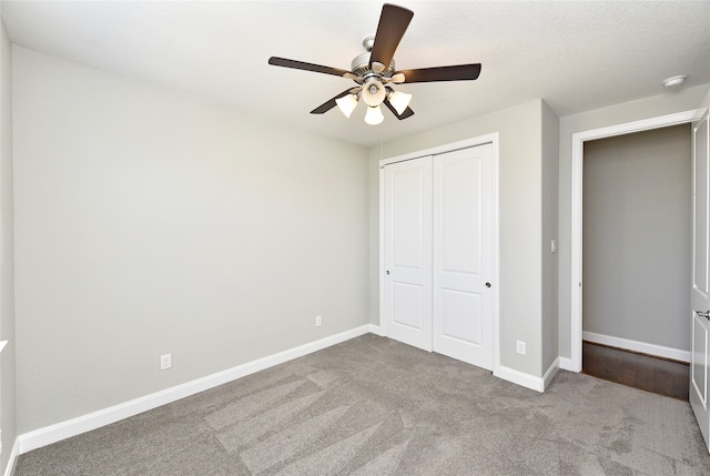 unfurnished bedroom with a textured ceiling, ceiling fan, light carpet, and a closet