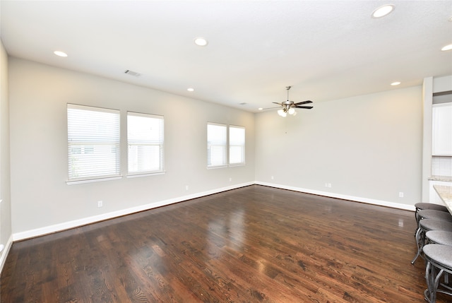 unfurnished living room featuring ceiling fan and dark wood-type flooring