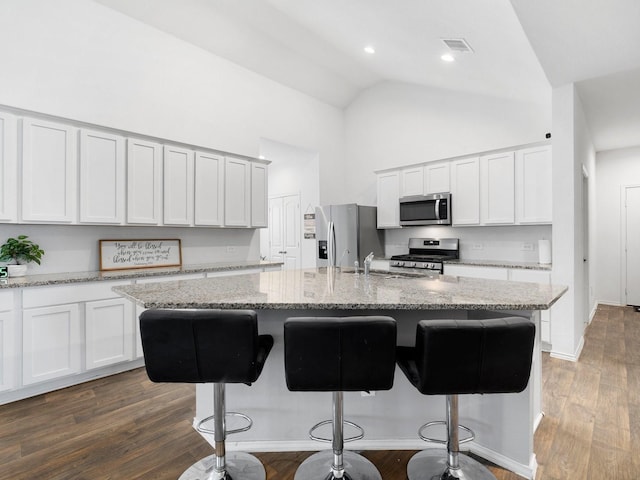 kitchen featuring a center island with sink, dark hardwood / wood-style flooring, stainless steel appliances, and a breakfast bar area