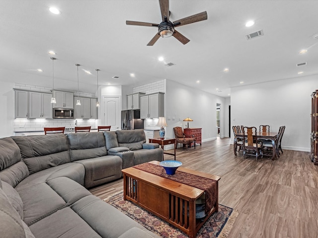 living room featuring light wood-type flooring and ceiling fan