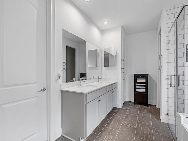 bathroom featuring a shower with door and vanity