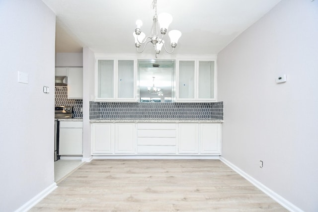 kitchen with a chandelier, white cabinets, exhaust hood, and electric range oven