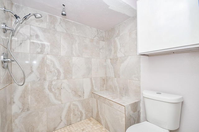 bathroom featuring a tile shower and toilet