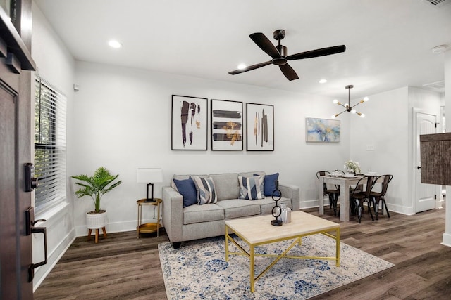 living room featuring ceiling fan with notable chandelier and dark hardwood / wood-style floors