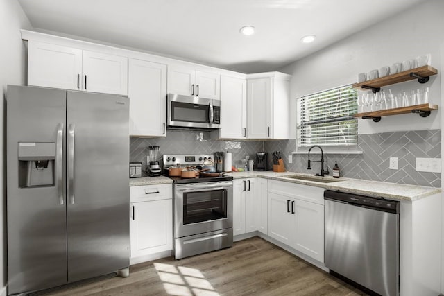 kitchen with stainless steel appliances, dark hardwood / wood-style floors, white cabinets, light stone counters, and sink